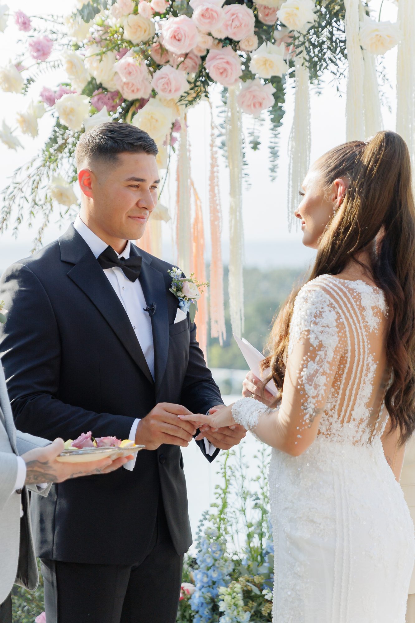 Ashleigh and James facing each other at the altar, exchanging rings under the floral arch at Villa Baan Phu Prana