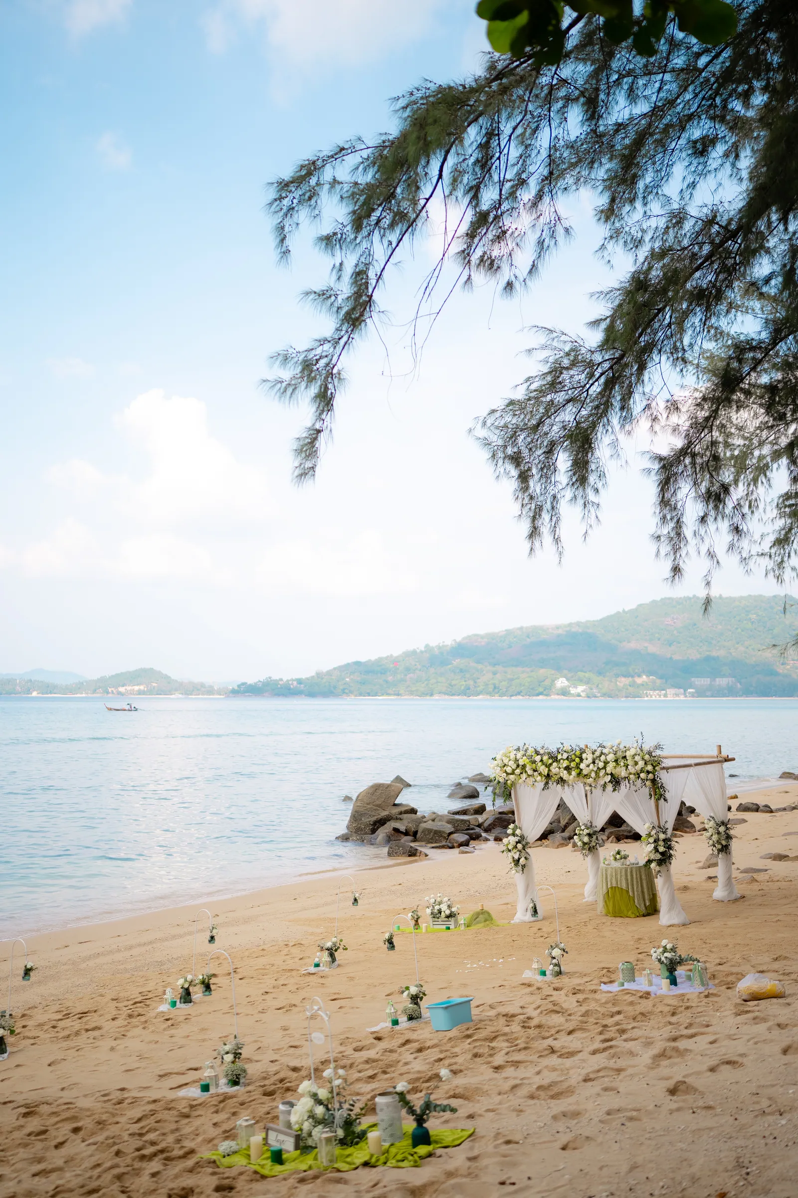 The empty ceremony setup on Hua Beach as the light drops — the bamboo arch on the sand, the sea and headland catching the last light