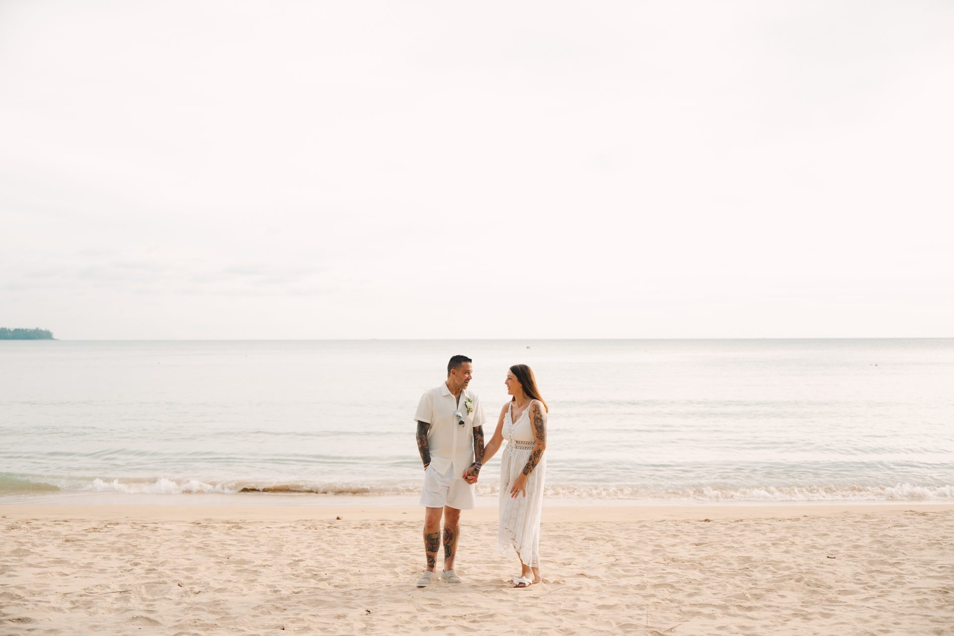 Joanne and Richard walking hand-in-hand along the shoreline at Layan Beach after their blessing