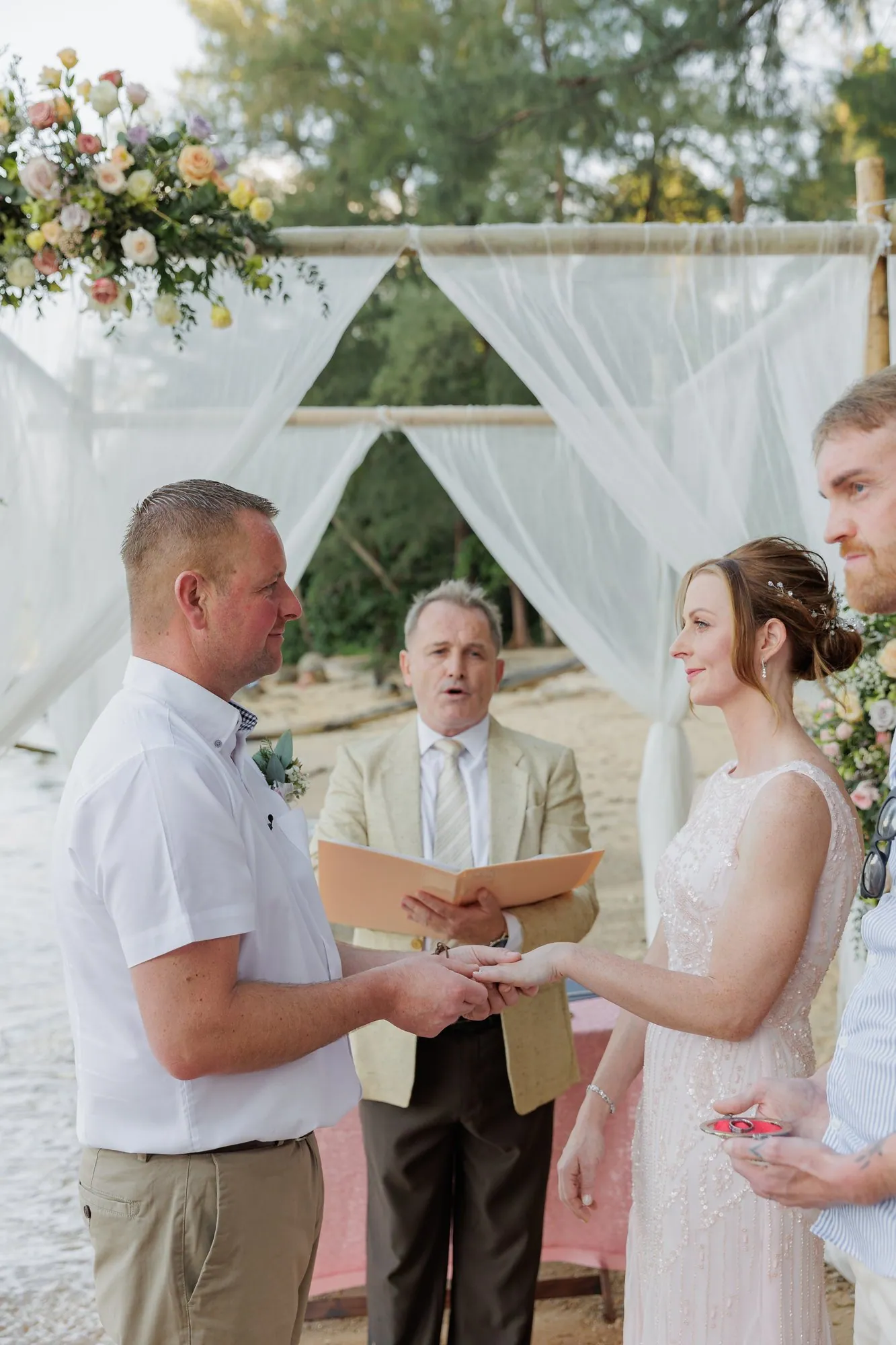 Amanda and John exchanging rings in front of Paul Cunliffe as celebrant at their Hua Beach wedding ceremony
