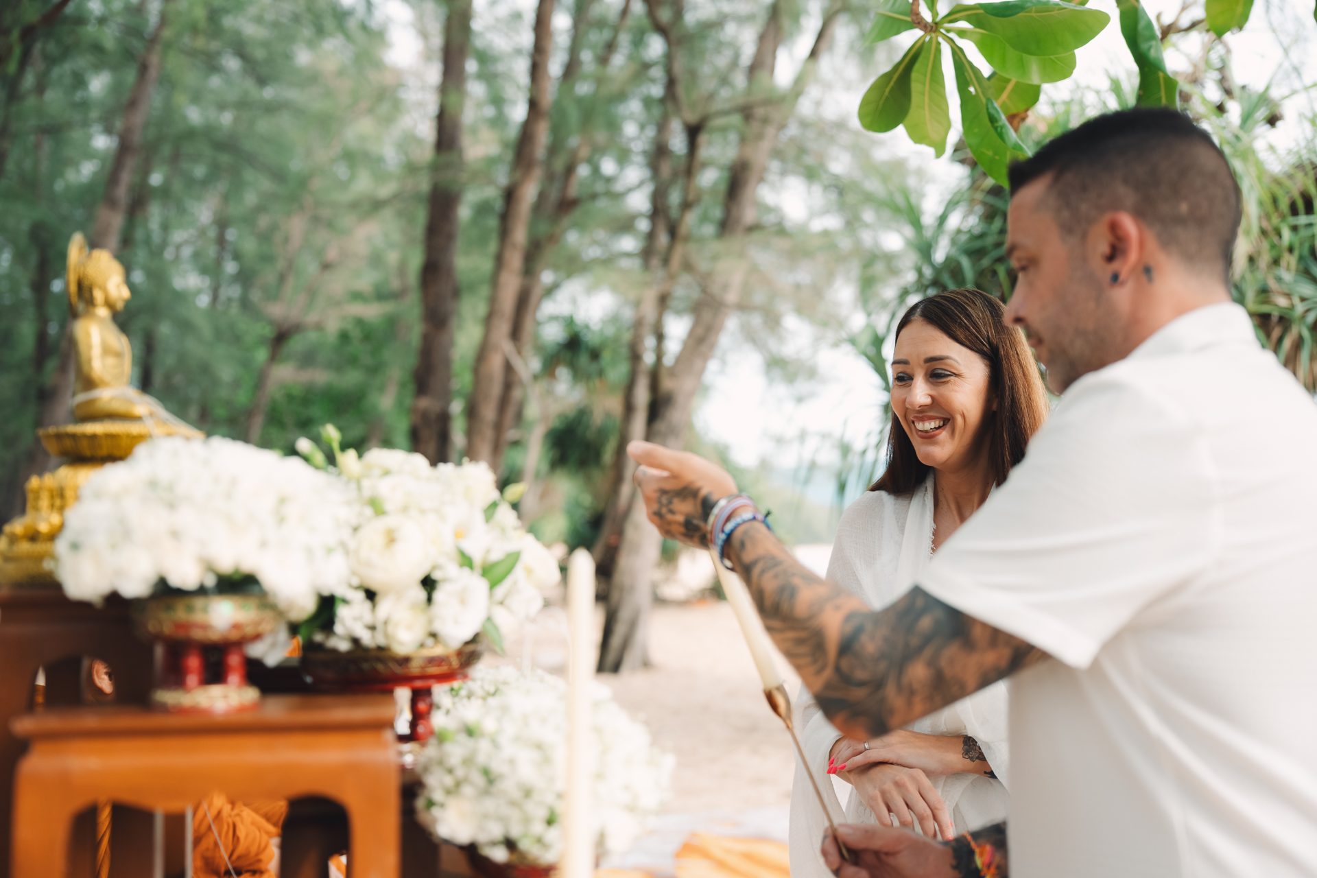 Joanne's soft white and green bridal bouquet held up against the trees at Layan Beach