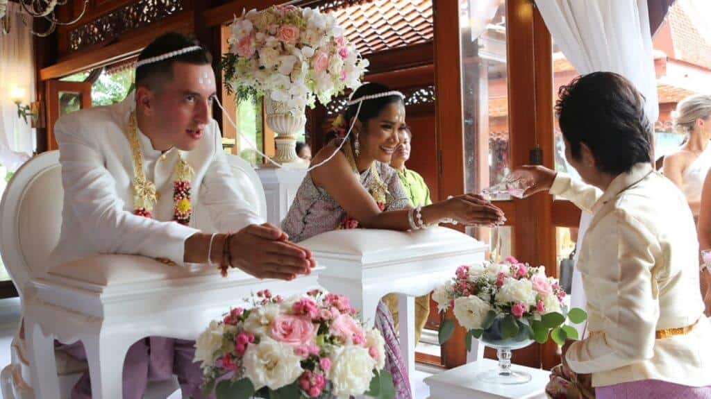 A Chut Thai wedding ceremony in Phuket — the bride and groom in traditional Thai wedding dress during the water-blessing ritual