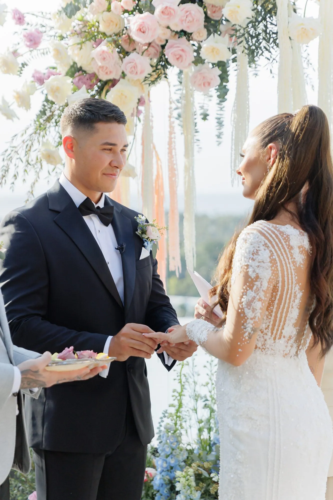 Ashleigh and James facing each other at the altar, exchanging rings under the floral arch at Villa Baan Phu Prana