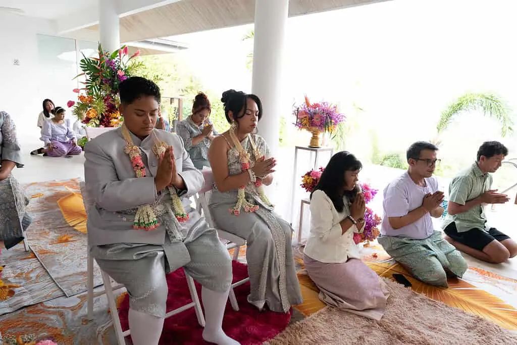 A Traditional Thai Wedding Ceremony in Phuket — the couple wearing floral garlands during the Sai Sin thread ritual.