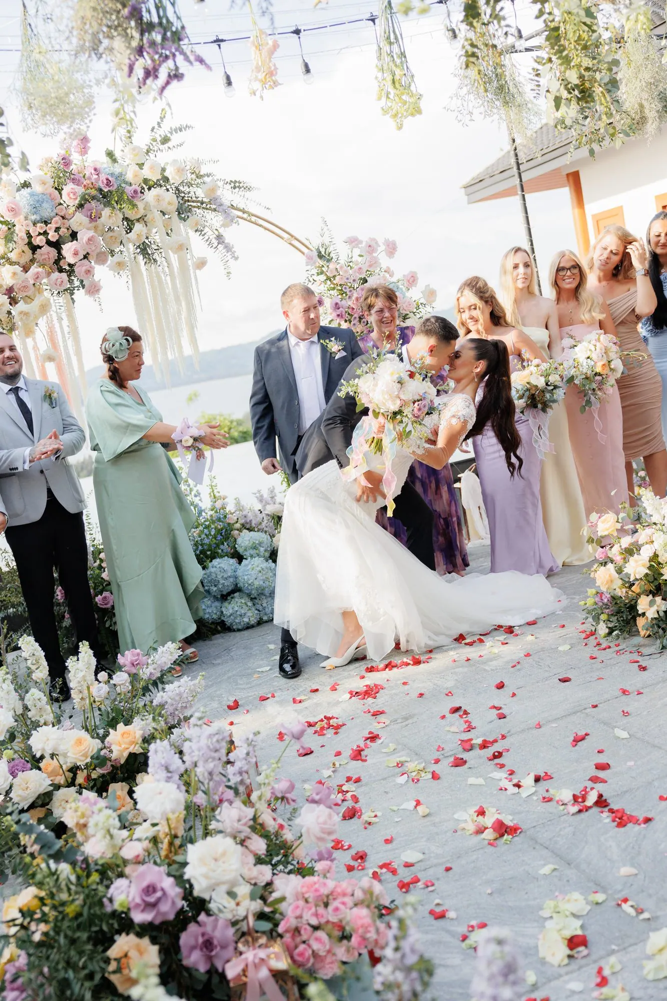 Ashleigh and James kiss at the end of the aisle after their ceremony, guests seated on either side and petals scattered on the ground