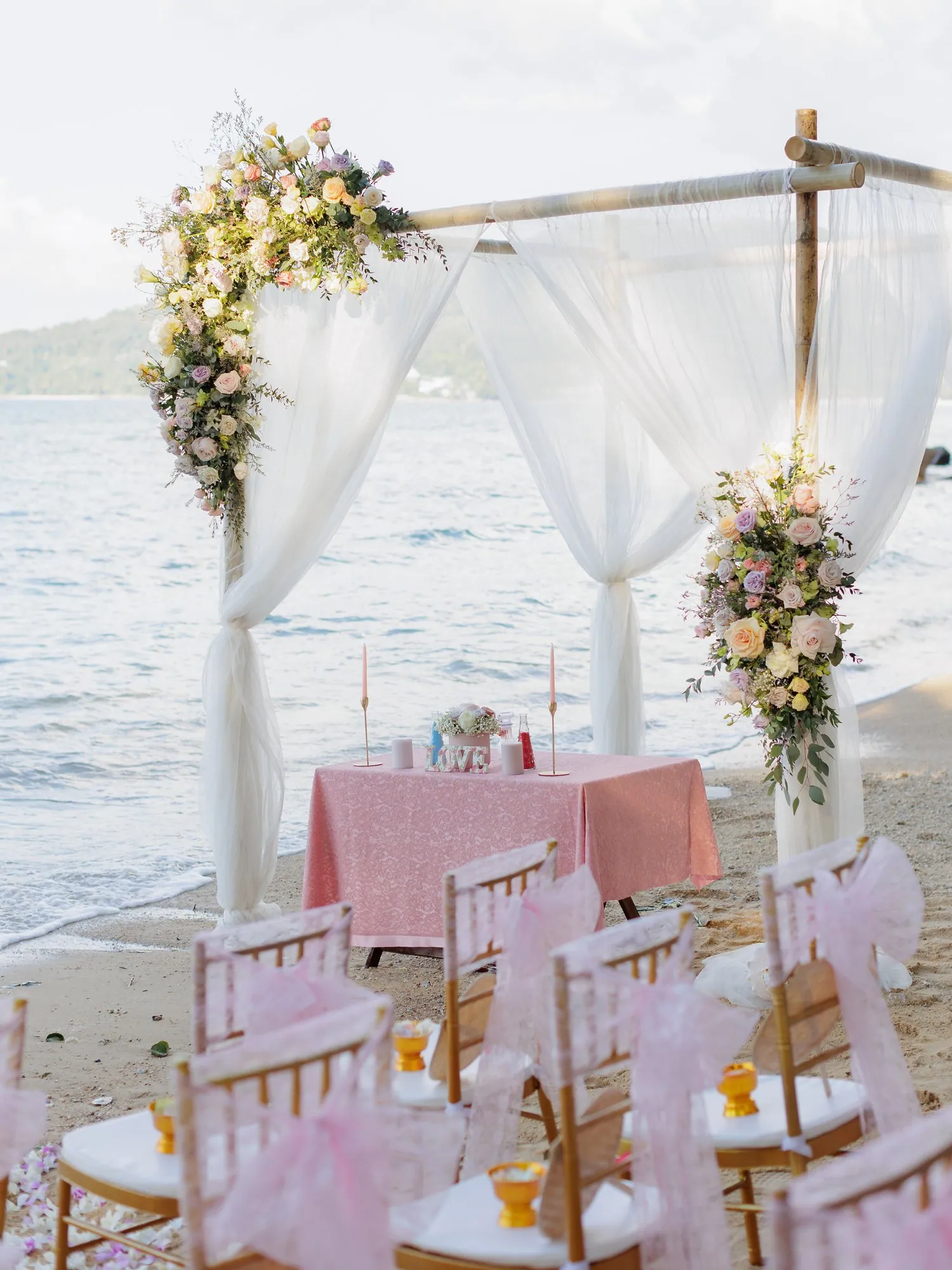 Amanda and John's beach wedding ceremony arch dressed in white drapes and pastel florals at Hua Beach, Phuket, on New Year's Day 2023