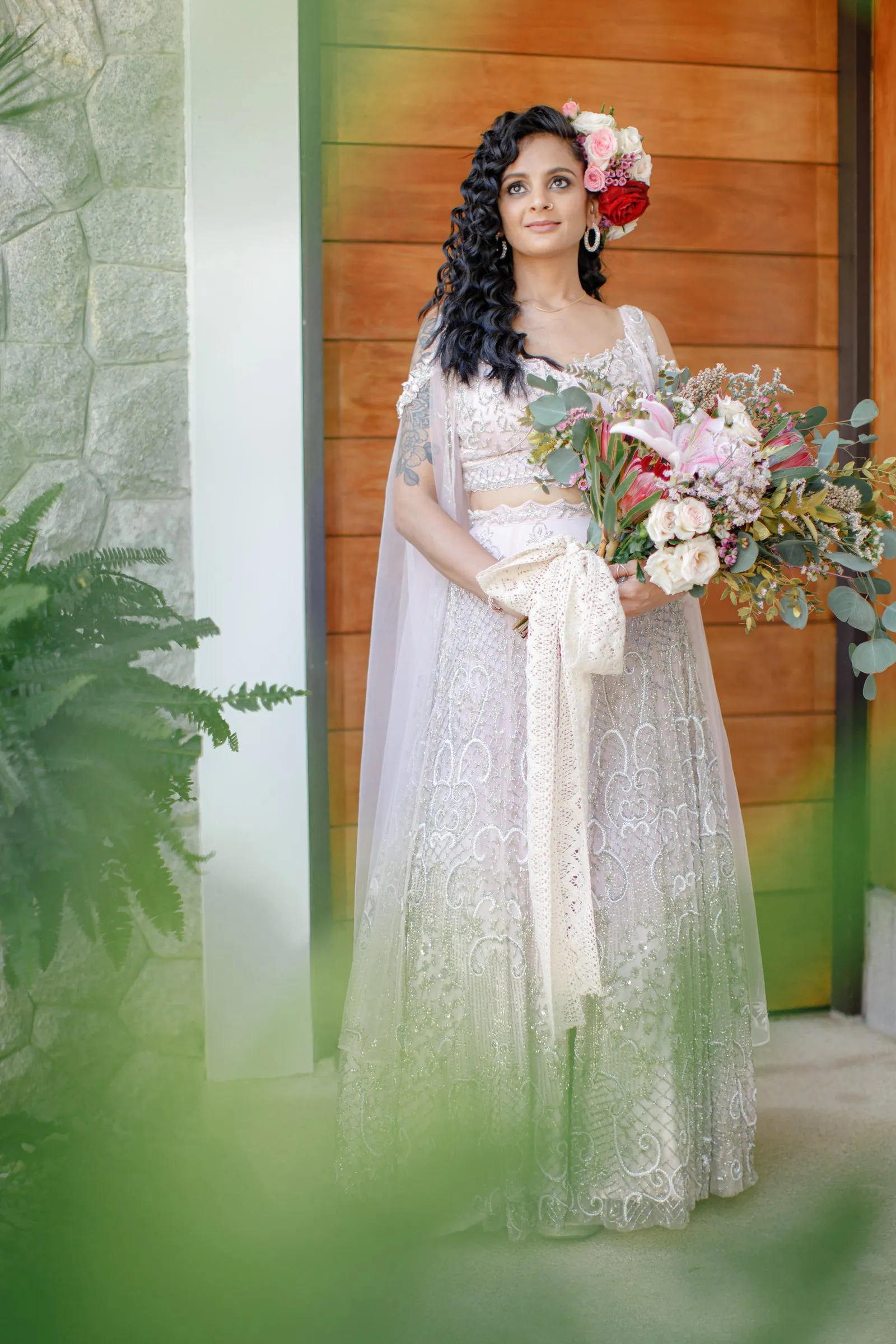 Poonam in a pale bridal outfit with a large gradient-pink bouquet at Villa Shanti