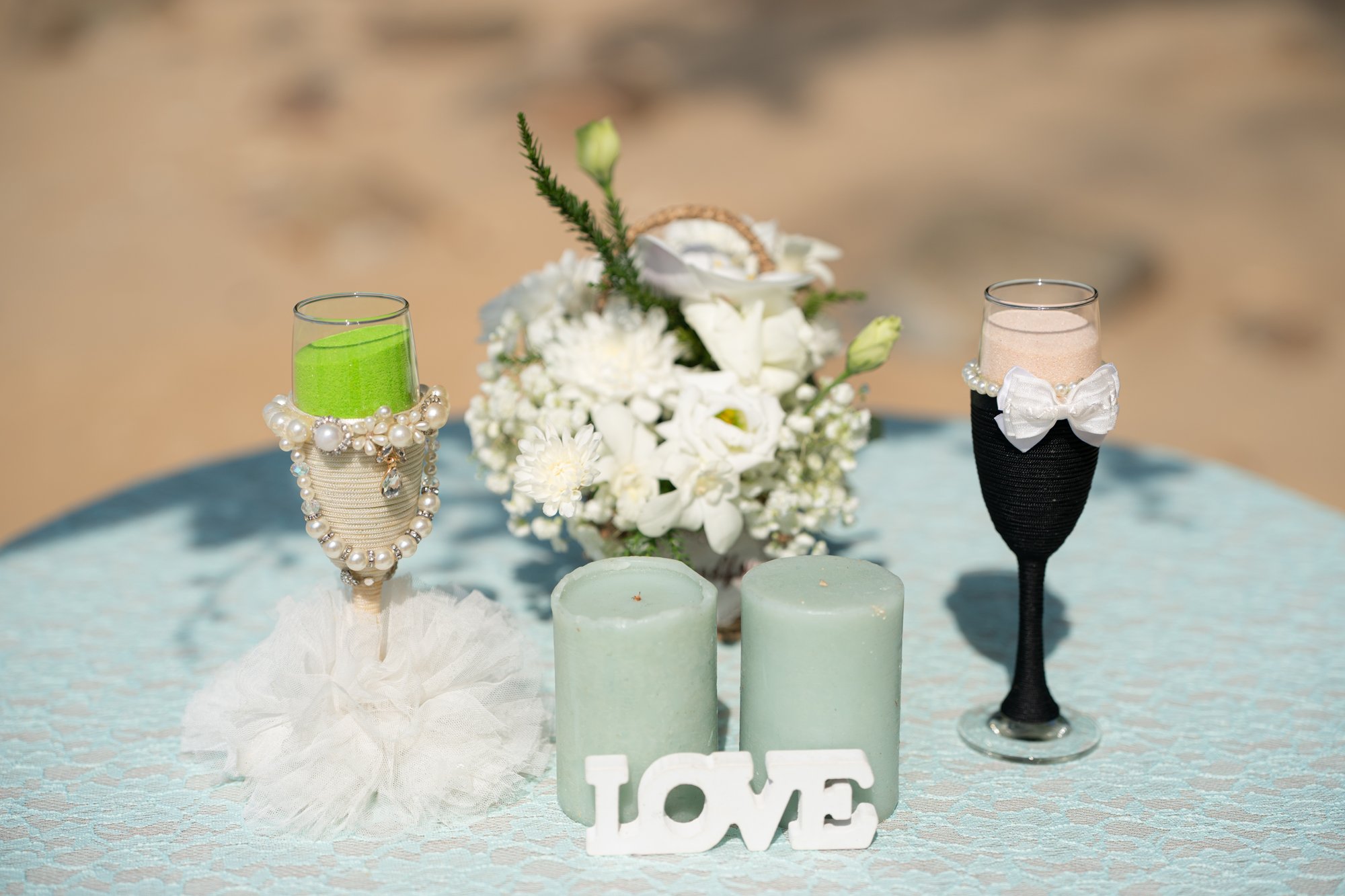 Mint green candles, a white peony arrangement and LOVE letters set out on a table at the villa before the ceremony