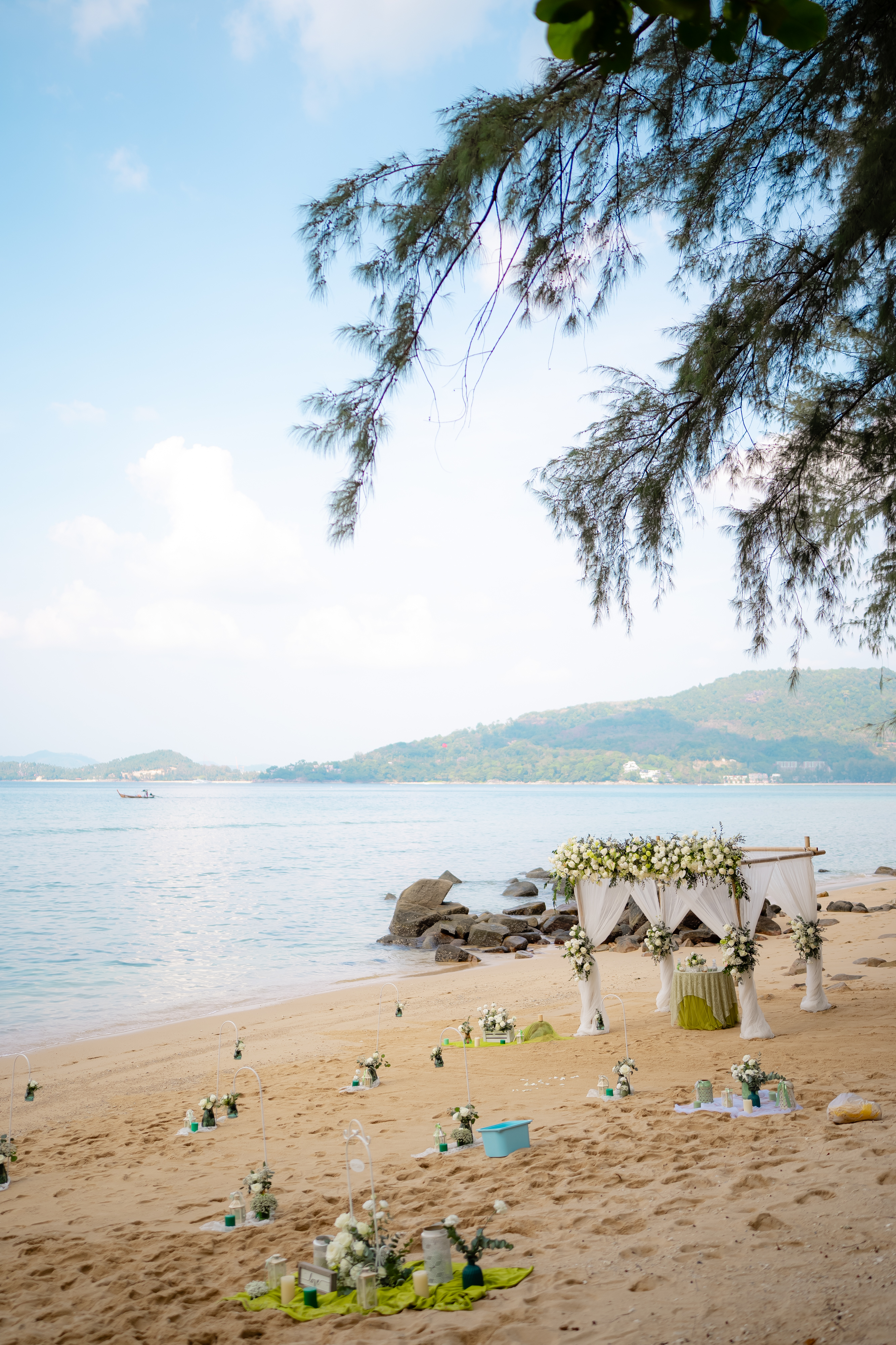 The empty ceremony setup on Hua Beach as the light drops — the bamboo arch on the sand, the sea and headland catching the last light
