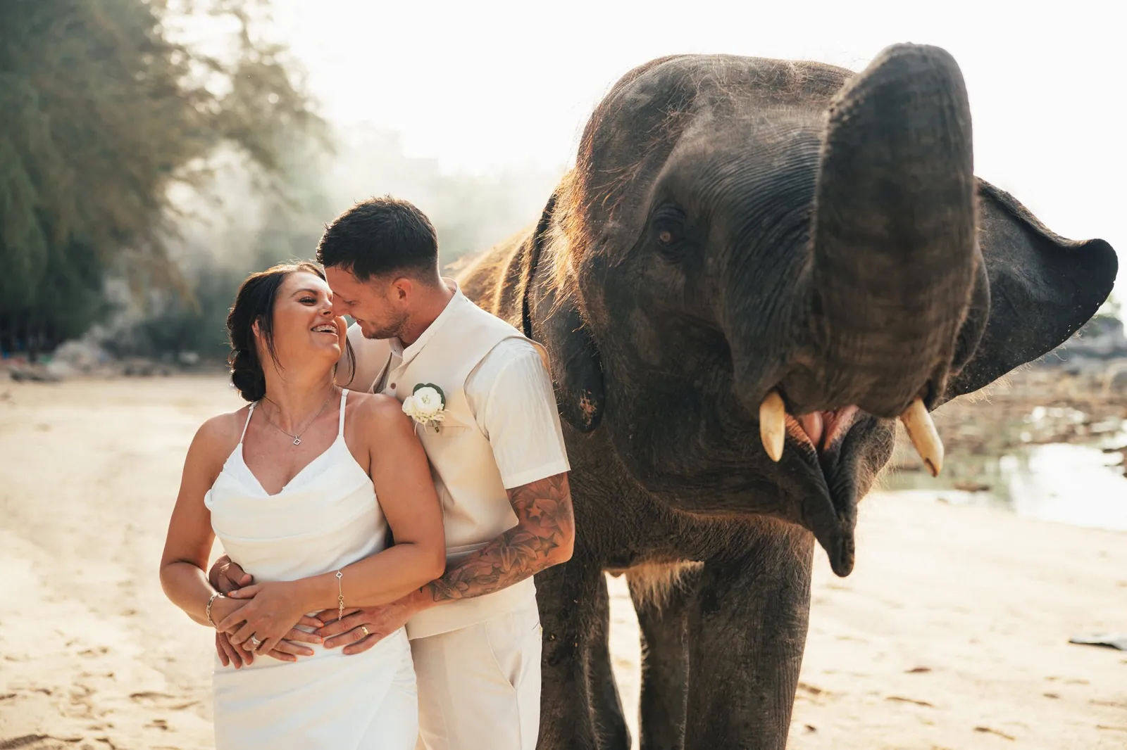 Jade and Nicky embracing on Hua Beach with the young elephant close beside them