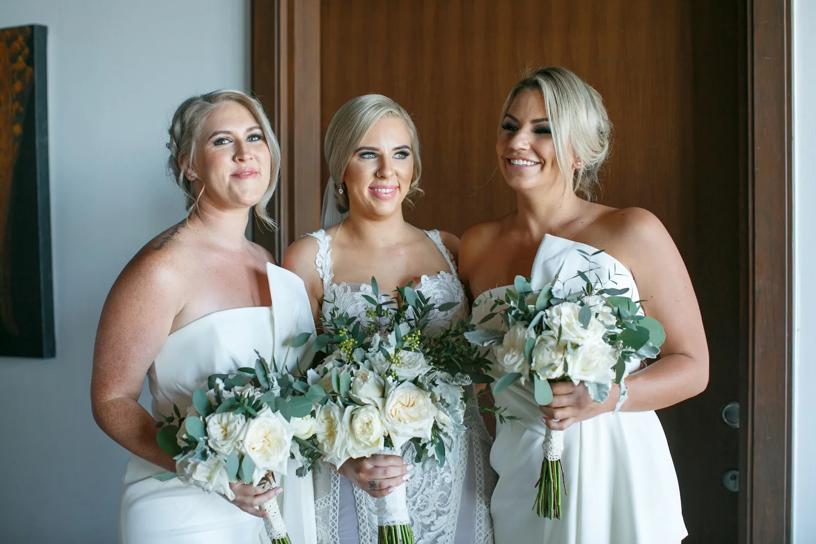 Kailey with her two bridesmaids holding white rose and eucalyptus bouquets on the morning of the wedding
