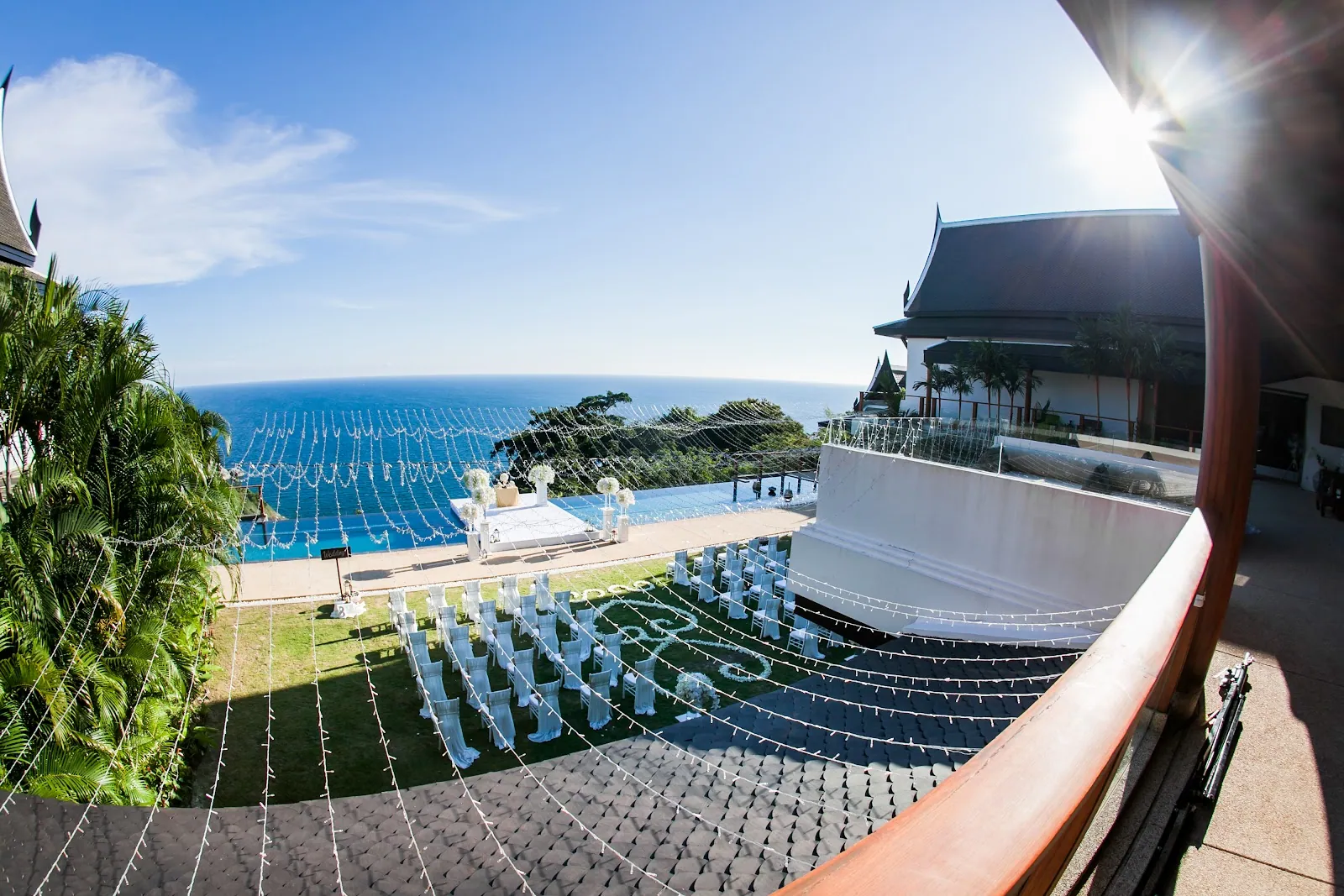 The Villa Aye ceremony lawn set for fifty guests — fairy lights strung above the aisle with the pool and Andaman Sea beyond