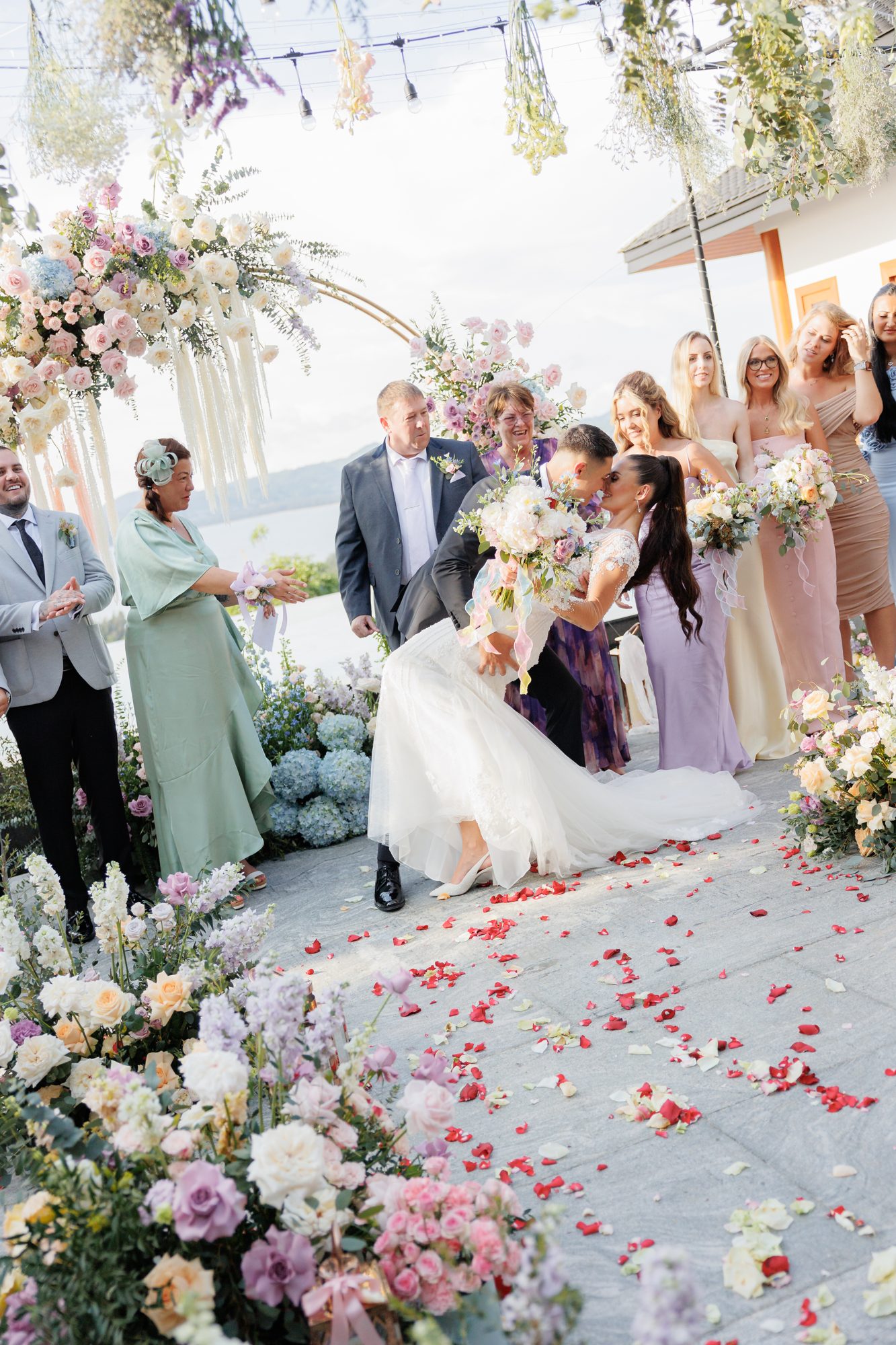 Ashleigh and James kiss at the end of the aisle after their ceremony, guests seated on either side and petals scattered on the ground