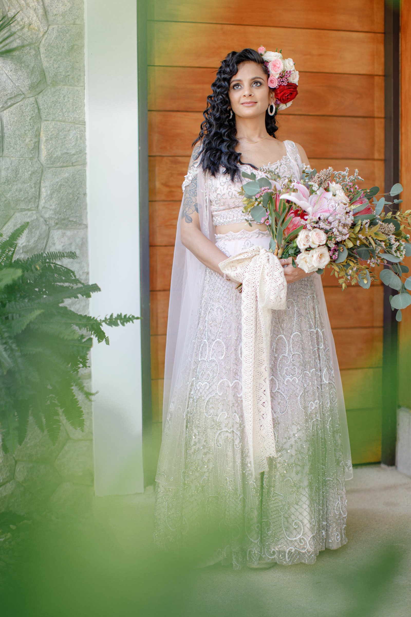 Poonam in a pale bridal outfit with a large gradient-pink bouquet at Villa Shanti