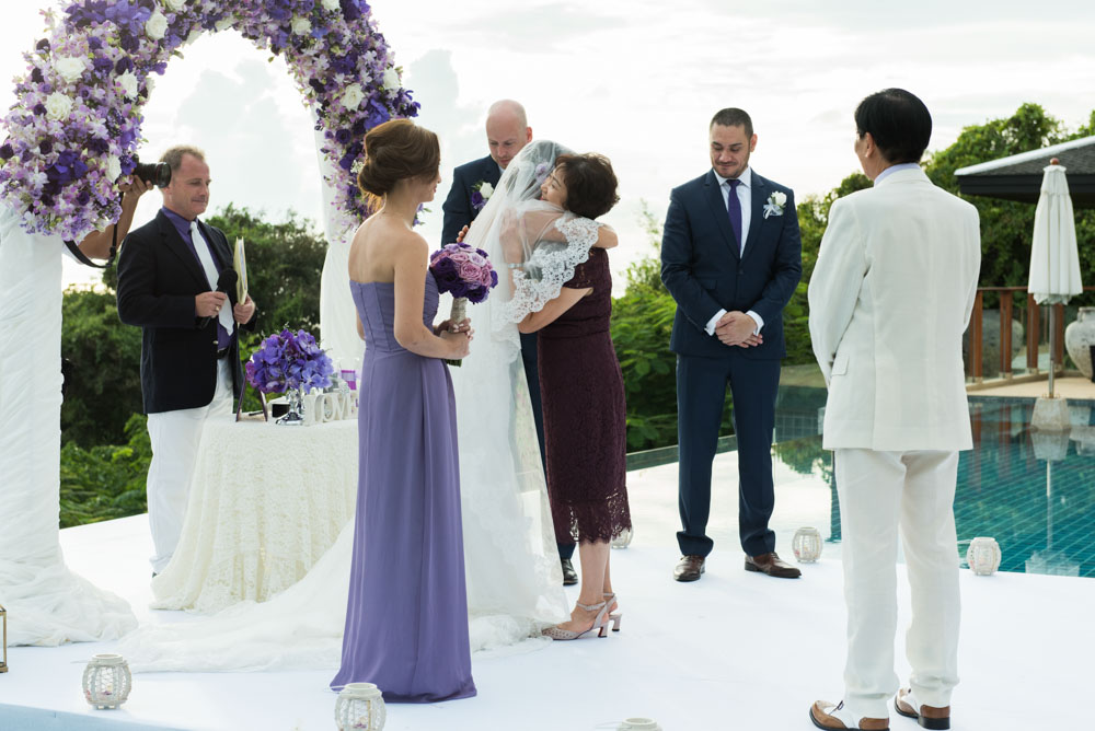 A quiet ceremony moment at Villa Aye — Gerda embraced by family under the purple arch